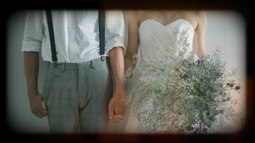 丸みのある暗いビネットとホコリや傷のノイズに包まれ手をつなぐ新郎新婦の写真をレトロなフィルム映像風に見せたシーン